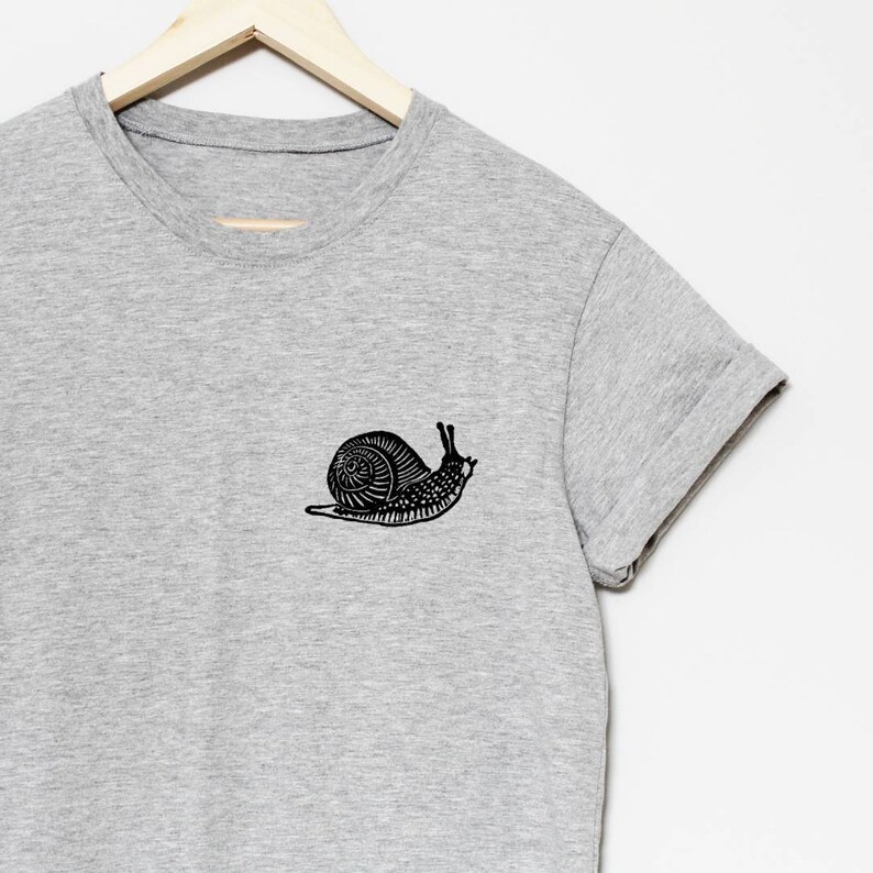 May include: A gray t-shirt with a black snail graphic on the left chest.