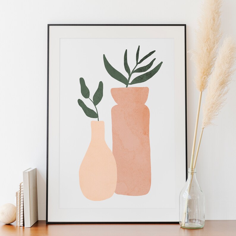 May include: A framed print of a minimalist art design featuring two vases with green leaves. The vases are peach and terracotta colored.