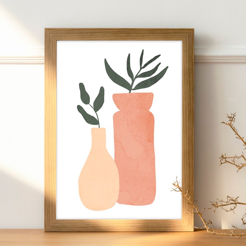 May include: A framed print of a minimalist illustration featuring two vases with green leaves. The vases are peach and pink and are on a white background.