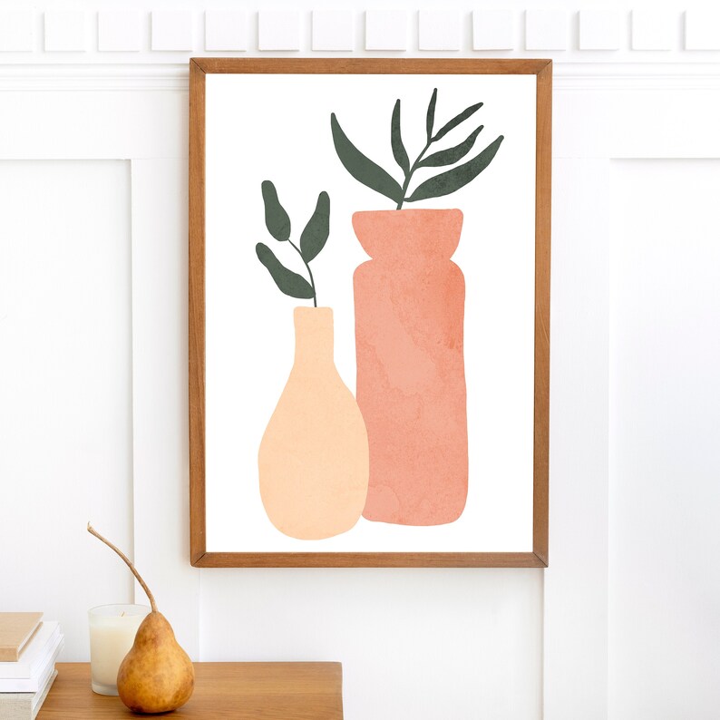 May include: A framed print of a minimalist art piece featuring two vases with green leaves. The vase on the left is peach colored and the vase on the right is a light pink color.