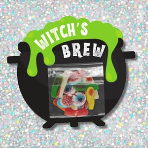 Op de afbeelding: Een Halloween-afbeelding met een zwarte ketel met de tekst "WITCH'S BREW" in wit en groen. In de ketel zit een doorzichtige zak vol kleurrijke gummy snoepjes in de vorm van oogballen, wormen en andere enge traktaties. De achtergrond is zilver en sprankelend.