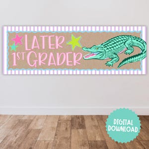 May include: A rectangular banner with the text "LATER 1ST GRADER" in pink, with a green alligator illustration. The banner has a brown background with a light blue and pink striped border, and star accents. A digital download icon is in the bottom right.