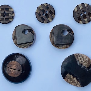 May include: Seven brown and black patterned buttons with two or four holes. The buttons are round and have a variety of geometric designs.