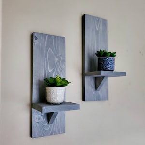 Puede incluir: Dos estantes de pared de madera gris con una peque&ntilde;a planta suculenta en maceta en cada estante.