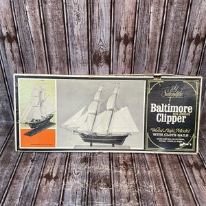 May include: A rectangular box for a Scientific Baltimore Clipper Dos Amigos wood ship model with cloth sails. The box features illustrations of the ship, the text Baltimore Clipper Dos Amigos, and states a length of 22.5 inches.