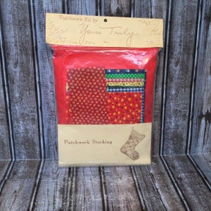 Puede incluir: Un kit de calcetín patchwork vintage en una bolsa de plástico transparente. El kit incluye tela roja y varios cuadrados de tela estampada en rojo, azul, amarillo y verde. El embalaje dice "Patchwork Kit by Yours Truly" y "Patchwork Stocking".