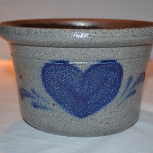May include: A gray ceramic planter with a blue heart design. The planter has a rough, textured surface.