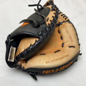 May include: A baseball glove with a black and tan color scheme. The glove has black stitching and an orange logo. The brand name "Easton" is visible. The model number "FL2000BKTN" is also visible.