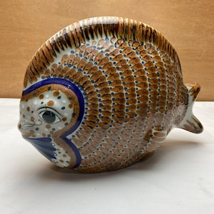 May include: A white ceramic mug with a black handle and the text "But First, Coffee" in a black, bold font. The mug is on a white surface. The mug is likely for hot beverages.