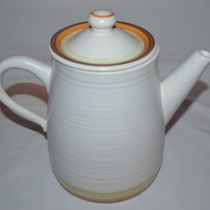 May include: White ceramic coffee pot with a brown and yellow striped lid. The pot has a textured, striped design.