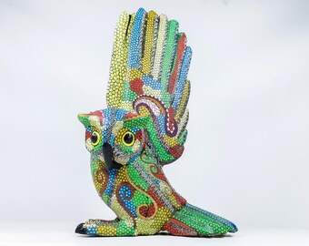Könnte beinhalten: Eine farbenfrohe Eulenfigur mit ausgebreiteten Flügeln, die ein lebendiges Punktmuster in Grün, Blau, Gelb und Rot aufweist. Die Eule hat große gelbe Augen und einen schwarzen Schnabel, was ein einzigartiges künstlerisches Design zeigt.
