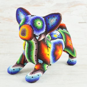 May include: A colourful beaded dog figurine with a blue, green, red, orange and purple colour scheme. The dog is in a sitting position with its head tilted to the side.