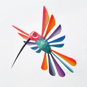 May include: A vibrant hummingbird sculpture with a long black beak and outstretched wings. The bird's head is red, with a white face and black eyes. The wings and tail feathers display a vibrant array of colours, including orange, yellow, blue, and purple.