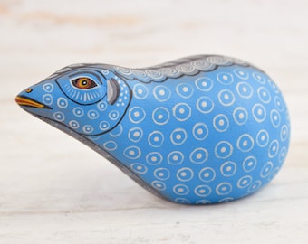 Könnte beinhalten: Eine handbemalte blaue Keramikfigur eines Tieres mit weißen und schwarzen Details. Die Figur hat eine abgerundete Form und ein stilisiertes Gesicht mit einem großen Auge.