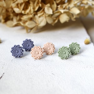 Könnte beinhalten: Drei Paar Blumen-Ohrstecker in den Farben Lila, Rosa und Grün. Die Ohrringe sind aus Polymer Clay gefertigt und haben ein strukturiertes, 3D-Design.