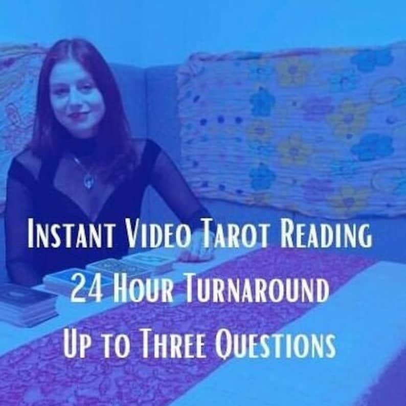 Pu&ograve; includere: Una donna &egrave; seduta a un tavolo con un set di carte dei tarocchi. Il testo sul tavolo recita "Instant Video Tarot Reading 24 Hour Turnaround Up to Three Questions".