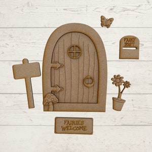 May include: Wooden fairy door craft kit with a sign that says "Fairies Welcome", a mailbox that says "Fairy Post", a mushroom, a flower, and a butterfly.