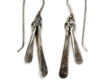 Può includere: Un paio di orecchini pendenti in argento con tre forme a goccia sottili e piatte in argento che pendono da ogni orecchino.