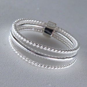 May include: A silver ring with three bands, two of which are twisted and one is smooth.