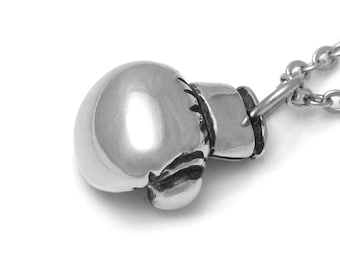 May include: A silver boxing glove pendant necklace. The pendant is detailed and realistic, with a textured surface. The chain is silver and has a lobster clasp.