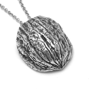 May include: A silver necklace with a detailed walnut pendant. The pendant is a realistic depiction of a walnut shell.