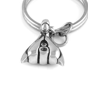 May include: A silver-toned metal keychain with a detailed anatomical design. The keychain features a loop for attaching keys.