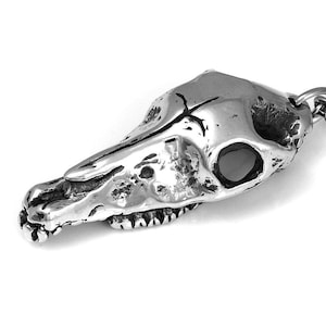 May include: A silver pendant necklace featuring a detailed skull of a horse. The pendant is attached to a silver chain.