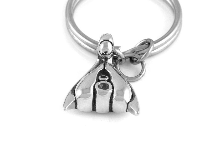 May include: A silver-toned metal keychain with a detailed anatomical design. The keychain features a loop for attaching keys.