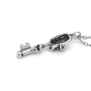May include: A silver key pendant necklace with a skull-shaped keyhole. The chain is silver and has a delicate link design.