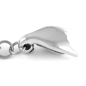 May include: A silver-toned keychain with a stylized heart-shaped charm. The charm is smooth and has a slightly curved shape.