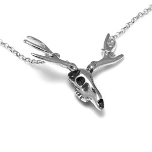 May include: A silver deer skull necklace with a detailed design of the skull and antlers. The necklace is on a silver chain.