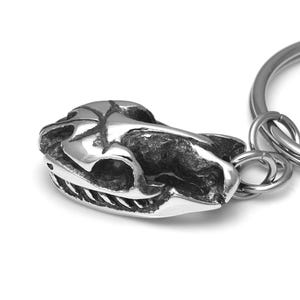 Pu&ograve; includere: Un portachiavi d'argento con un ciondolo a forma di teschio dettagliato. Il teschio &egrave; in metallo e ha una superficie testurizzata.