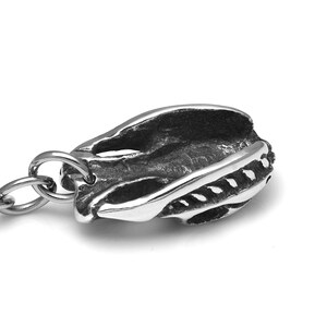 Pu&ograve; includere: Un portachiavi argentato con un designo di teschio dettagliato. Il teschio &egrave; aperto nella parte superiore e ha una superficie testurizzata. Il portachiavi &egrave; attaccato a un anello argentato.