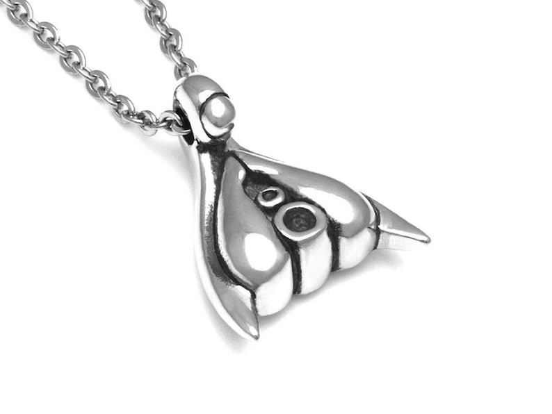 Puede incluir: Un collar con un colgante de plata con un dise&ntilde;o abstracto &uacute;nico. El colgante tiene una forma redondeada con dos peque&ntilde;os c&iacute;rculos en el centro.