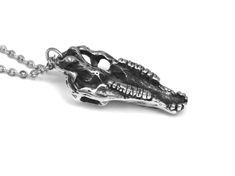 May include: Silver pendant necklace featuring a detailed skull of a dolphin or porpoise. The pendant is attached to a silver chain.