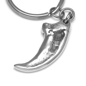 Puede incluir: Llavero de plata con un dije de garra detallado. La garra es una representación realista de una garra de animal afilada y curvada.