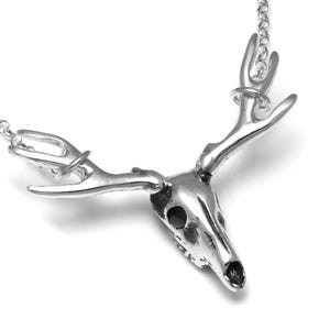 May include: Silver necklace with a detailed deer skull pendant and antlers.