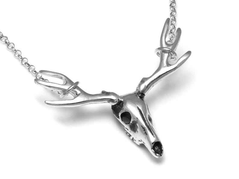 May include: Silver necklace with a detailed deer skull pendant and antlers.