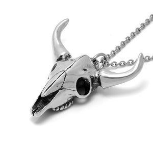 K&ouml;nnte beinhalten: Eine silberne Halskette mit einem detaillierten Stierkopf-Anh&auml;nger. Der Anh&auml;nger ist an einer silbernen Kette befestigt.