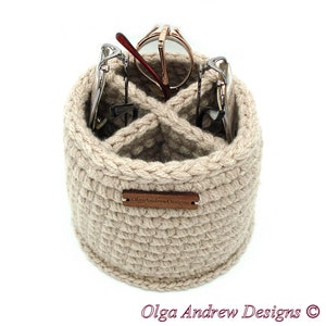 May include: Beige crocheted glasses holder with four slots for glasses. The holder has a wooden tag that says "OlgaAndrewDesigns".