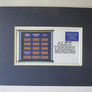 May include: A framed image of a stamp commemorating Alex Trebek, the host of the game show Jeopardy!. The stamp features a blue and white image of a game show board with the text "Alex Trebek First Day of Issue July 22, 2004 | Culver City, CA 90232".