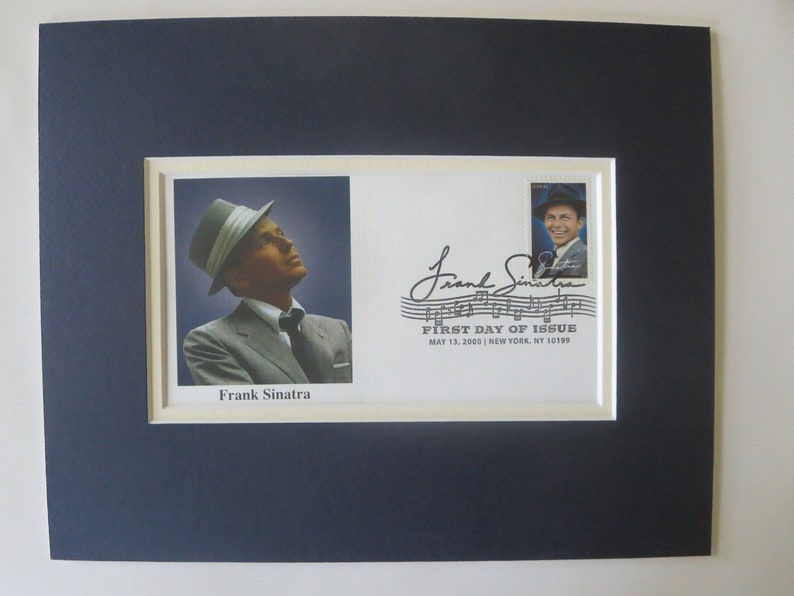 May include: A black and white photo of Frank Sinatra on a white stamp with a blue border. The stamp is part of a larger white envelope with a black and white signature and the text "Frank Sinatra" and "FIRST DAY OF ISSUE MAY 13, 2008 | NEW YORK, NY 10199".
