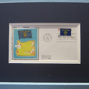 May include: A first day of issue envelope for the 33rd state admitted to the United States, Oregon. The envelope features a stamp with the Oregon state flag and a map of the state with the capital city Salem marked. The envelope is dated February 14, 1859.