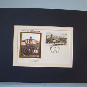 May include: A framed commemorative stamp featuring a vintage illustration of the University of Wisconsin-Madison campus. The stamp is titled "University of Wisconsin" and "USA 20". The stamp is dated "Feb 5, 1999" and has a postmark from Madison, WI.