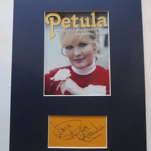 Peut inclure: Une photographie dédicacée de Petula Clark, chanteuse et actrice britannique, avec un passe-partout bleu et un passe-partout jaune. L'image montre Petula Clark tenant une fleur blanche. Le texte sur l'image est "Petula Clark's Legendary 1968 TV Special with guest Harry Belafonte".