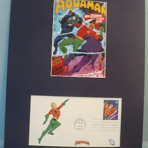 May include: A framed image of a comic book featuring Aquaman, a superhero who can control water. The comic book cover features Aquaman fighting a villain in the ocean. The image also includes a stamp featuring Aquaman, with the text "First Day of Issue".