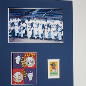 May include: A framed photo of the 1955 World Series featuring the Brooklyn Dodgers and the New York Yankees. The photo includes a group shot of the Dodgers players and a vintage baseball card of Jackie Robinson.