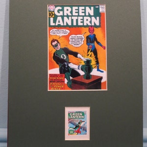 Op de afbeelding: Een vintage Green Lantern-comicboekomslag met een groene superheld met een kracht ring die vecht tegen een roodhuidige schurk. De comicboekomslag is ingelijst met een kleinere Green Lantern-comicboekomslag in de rechterbenedenhoek.
