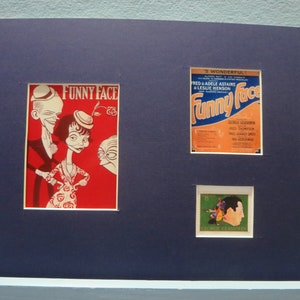Puede incluir: Una impresión enmarcada en azul con un programa de teatro vintage de Funny Face con una caricatura de Fred Astaire y Adele Astaire. El programa es de color naranja, azul y blanco. Una impresión enmarcada más pequeña de un sello postal vintage con una caricatura de George Gershwin se encuentra debajo del programa.