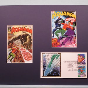 May include: A framed collection of Aquaman comic book covers and a stamp featuring Aquaman. The covers feature Aquaman fighting a creature from the deep and Aquaman fighting Black Manta. The stamp features Aquaman swimming through water.